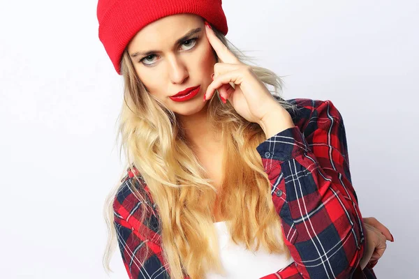 Красива молода хіпстерська блондинка з яскравим сексуальним макіяжем у стильній міській сорочці та червоному капелюсі, білий фон . — стокове фото