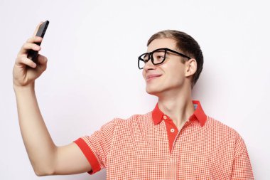 Fotoğrafta kamerada gülümseyen yakışıklı bir adam selfie çekiyor.