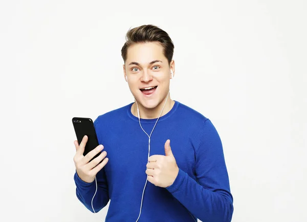 Feliz joven y elegante hombre ajustando sus auriculares y sonriendo mientras está de pie sobre fondo blanco — Foto de Stock