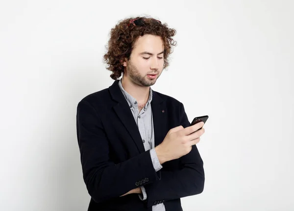 Lächelnder junger Mann mit Smartphone und Blick darauf. — Stockfoto