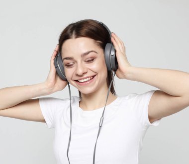 Güzel genç bir kadın kulaklıkla müzik dinliyor.  