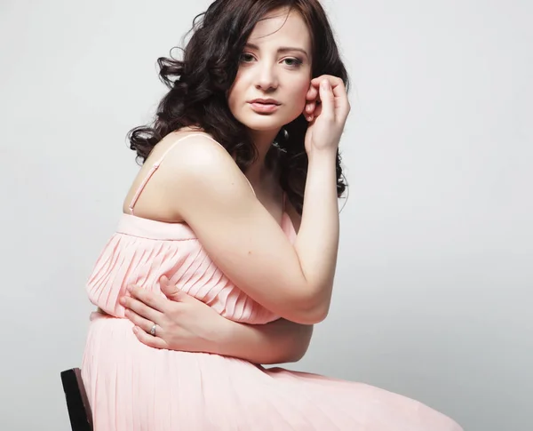 Young woman with curly hair wearing pink dress — Stock Photo, Image