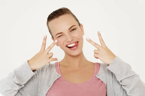 Retrato de mujer hermosa mirando a la cámara con sonrisa y mostrando signo de paz con los dedos —  Fotos de Stock