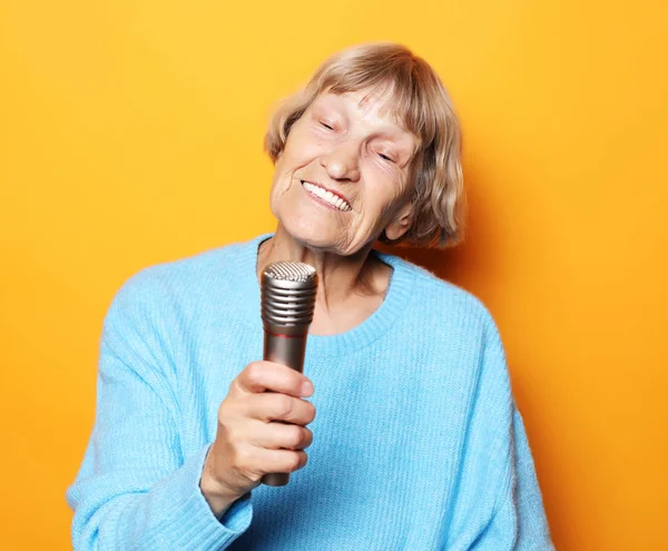 Lifestyle and people concept: Χαρούμενη ηλικιωμένη γυναίκα να τραγουδάει με μικρόφωνο, να διασκεδάζει, να εκφράζει μουσικά ταλέντα — Φωτογραφία Αρχείου