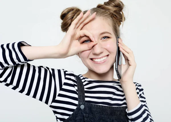 Mujer alegre sonriendo, demostrando dientes blancos, mirando a la cámara a través de los dedos en buen gesto . — Foto de Stock