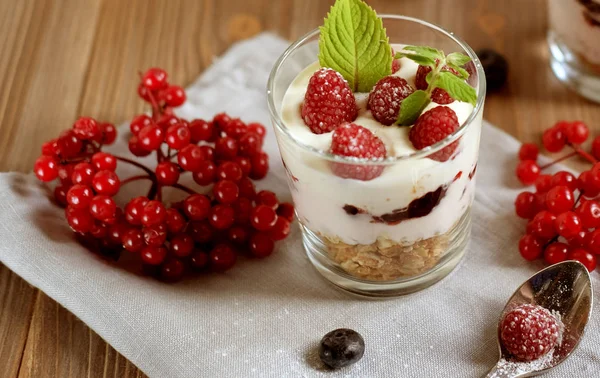Glad frukost - yoghurt med müsli och bär på ett träbord — Stockfoto