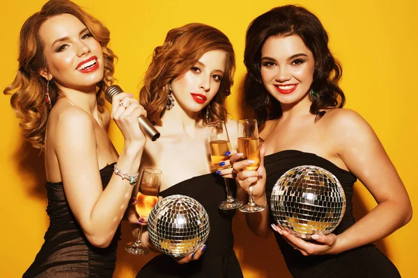 Encantadoras jovens mulheres com bolas de discoteca bebendo champanhe — Fotografia de Stock