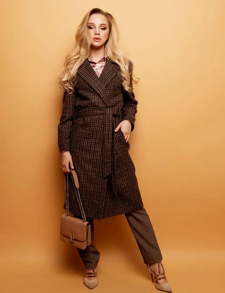 Мода, люди и образ жизни: женщина с длинными кудрявыми волосами носит кашемировое пальто и держит в руках сумочку. — стоковое фото