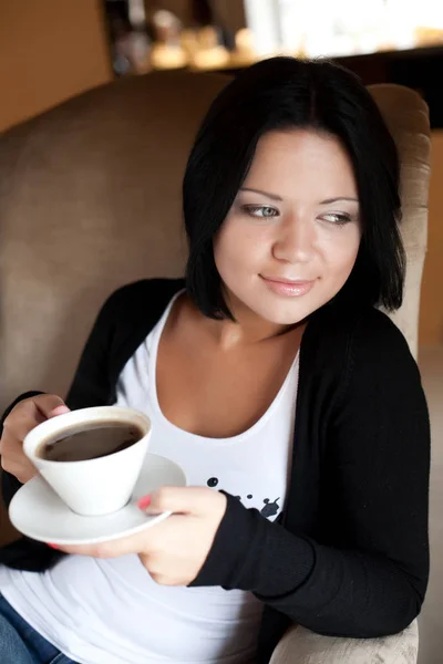 Młoda kobieta siedzi w kawiarni i pije kawę — Zdjęcie stockowe