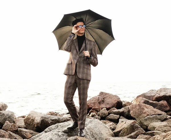 Jovem elegante com guarda-chuva em pé perto do mar — Fotografia de Stock