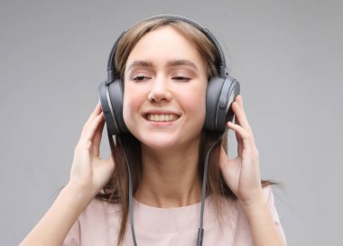 Kulaklıklı genç bir kadın müzik dinliyor.