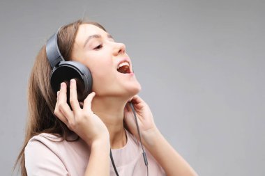 Kulaklıklı genç bir kadın müzik dinliyor.