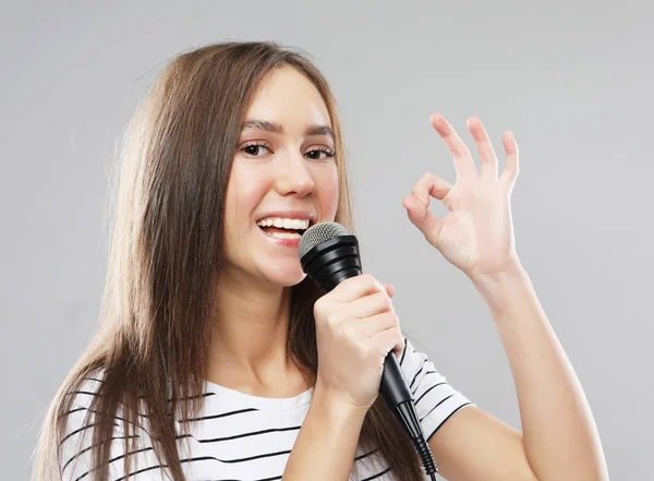 Piękno modelu dziewczyna piosenkarka z mikrofonem na jasnoszarym tle — Zdjęcie stockowe
