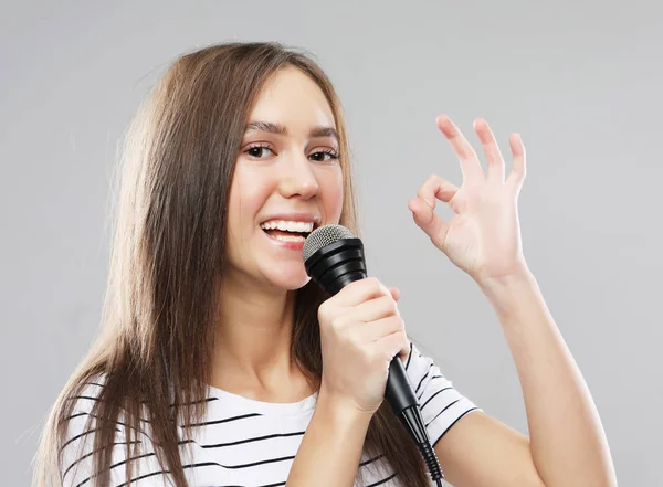 Belleza modelo chica cantante con un micrófono sobre fondo gris claro —  Fotos de Stock