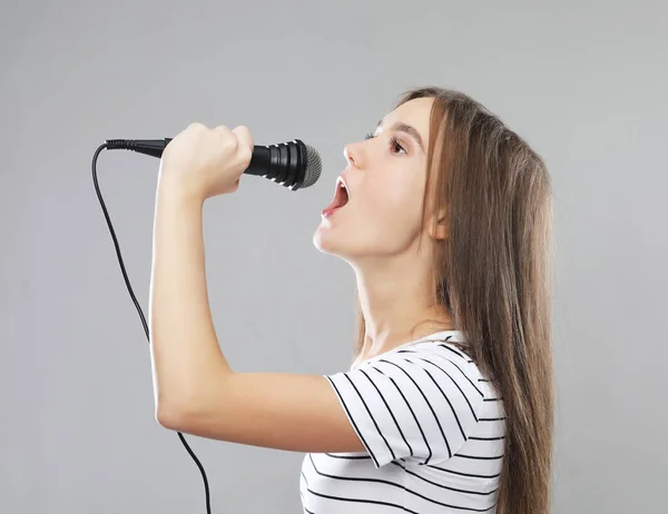 Schönheit Modell Mädchen Sängerin mit einem Mikrofon über hellgrauem Hintergrund — Stockfoto