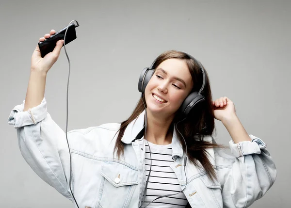 Belle jeune femme à l'écoute de la musique dans les écouteurs avec smartphone — Photo