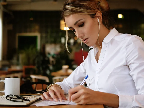 Primer plano de la joven hermosa mujer de negocios escribiendo en el cuaderno en la cafetería . — Foto de Stock