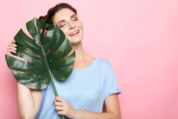 Pembe backfround üzerinde yeşil yaprakları ile teen modeli — Stok fotoğraf
