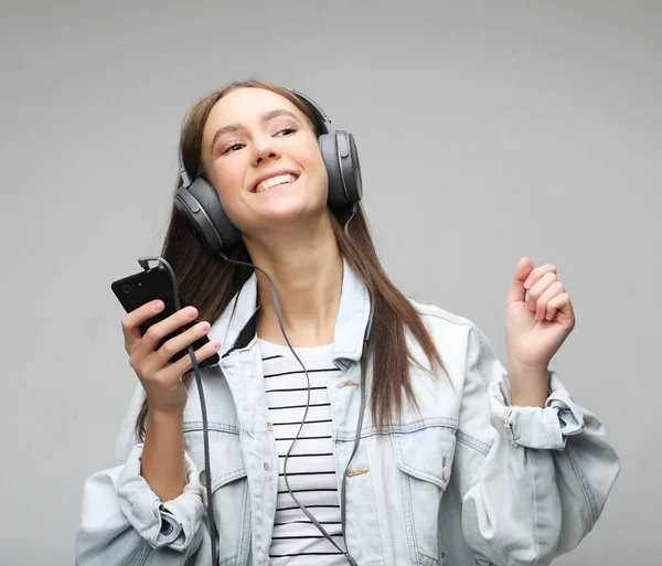 Belle jeune femme à l'écoute de la musique dans les écouteurs avec smartphone — Photo