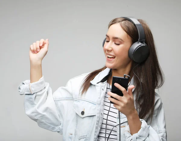 Vacker ung kvinna som lyssnar på musik i hörlurar med smartphone — Stockfoto