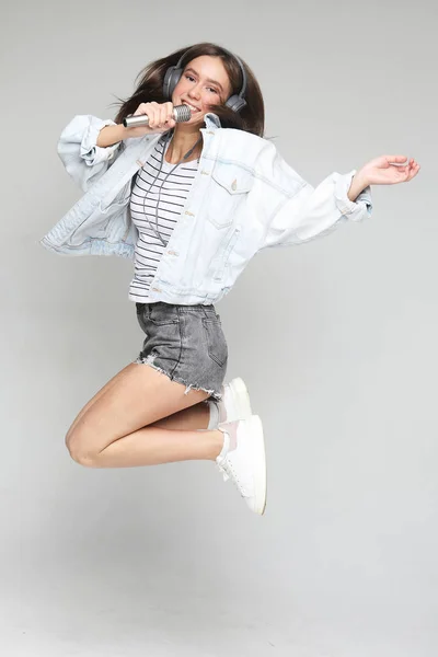 Lycklig kvinna med mikrofon hoppar och sjunger — Stockfoto