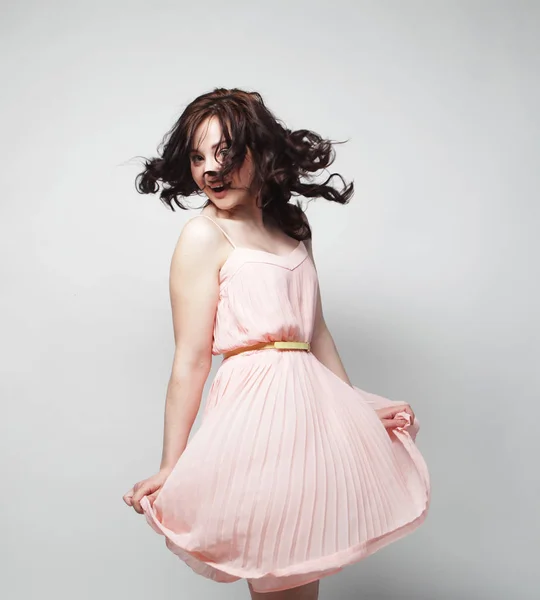 Fiatal nő, göndör haj, rózsaszín ruhát visel — Stock Fotó