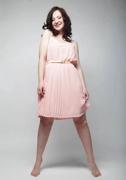 ピンクのドレスを着ての巻き毛を持つ若い女性 — ストック写真