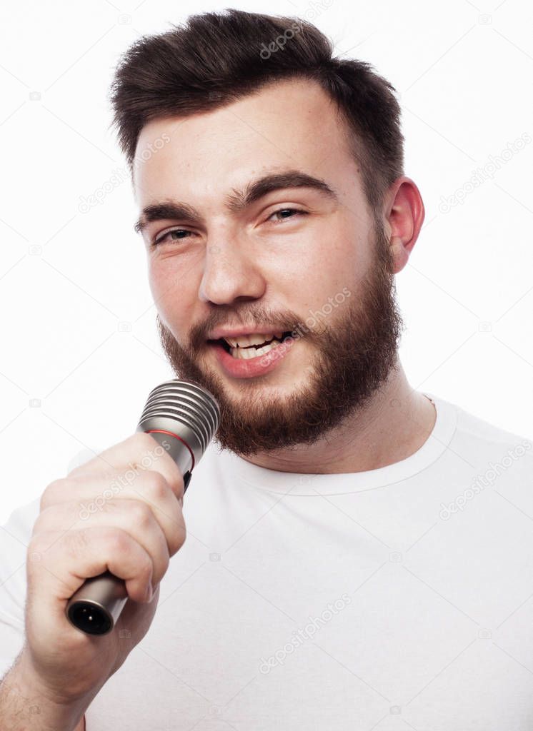 young bearded man in white shirt singing in microphone