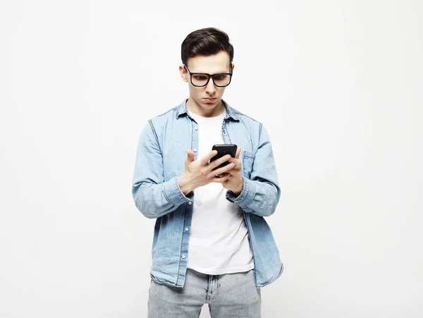 Feliz joven en gafas escribiendo sms sobre fondo blanco — Foto de Stock