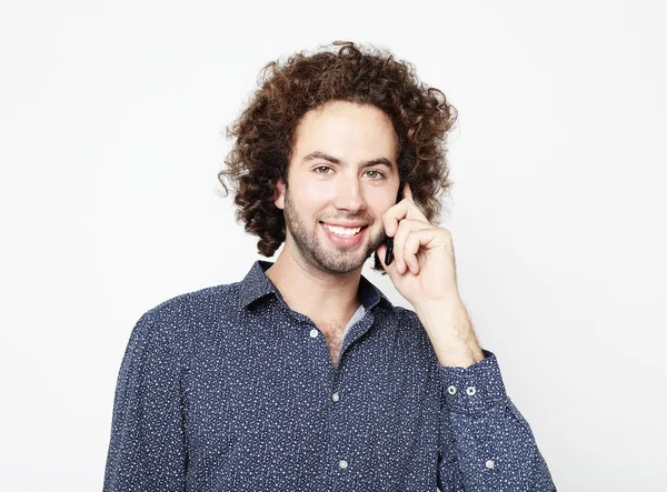 Sonriente joven hablando por teléfono inteligente y mirando a la cámara — Foto de Stock