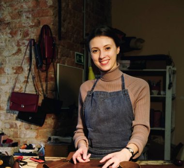 kadın bir çanta yapma stüdyosu çalışır, detayları keser