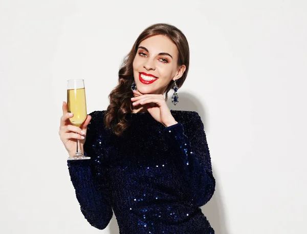 Mooi meisje in een cocktailjurk met 's avonds make-up en krullen met een glas Champagne — Stockfoto