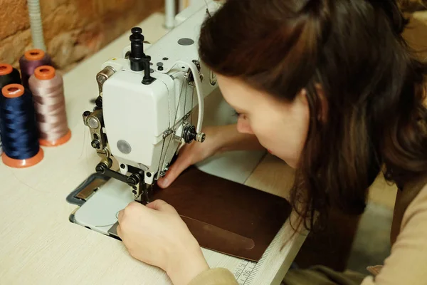 Closeup on woman sewing leather handbag