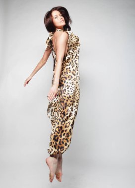 Genç sevimli kadın şifon elbise gri arka plan üzerinde atlama