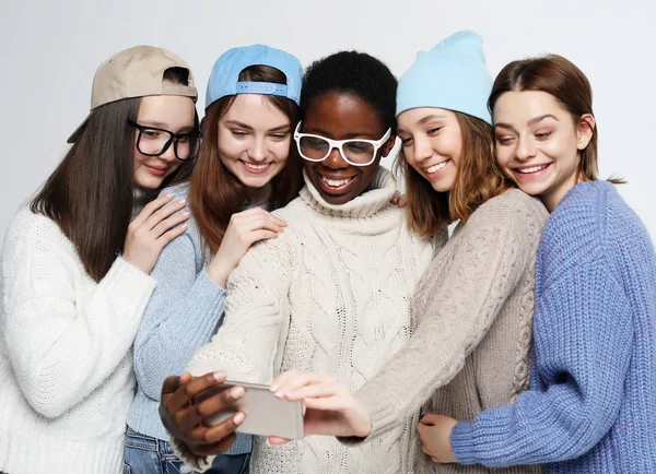 カジュアルな服を着て5つの異なる国の女の子は、白の背景上のスマートフォンで自分撮りを作ります — ストック写真