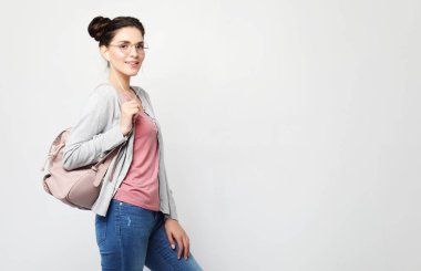 Saçlı bir kadın. Sırt çantalı günlük kıyafetler giyiyor.