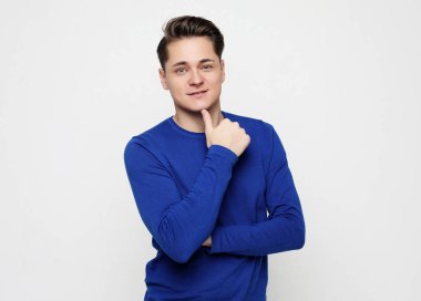 Beyaz arka plan aleyhine rahat ayakta giyen akıllı bir genç adamın portresi