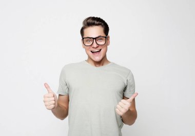  Mutlu genç yakışıklı adam el kol hareketi yapıyor ve ağzını kapalı tutuyor.