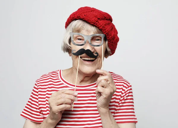 Estilo de vida e conceito de pessoas: avó engraçada com bigode falso e óculos, ri e se prepara para a festa — Fotografia de Stock