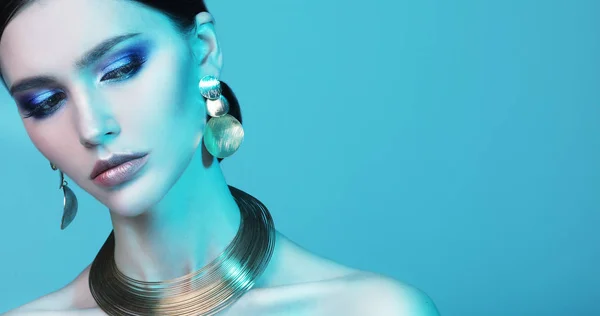 Modelo de moda bonita usando jóias elegantes na luz de cor — Fotografia de Stock