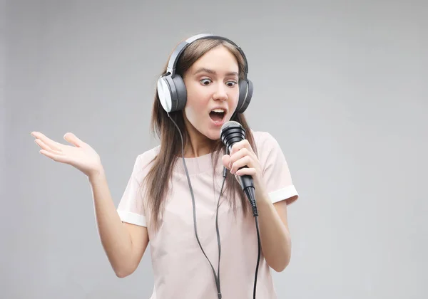 Fille expressive chantant avec un microphone et écouteurs — Photo