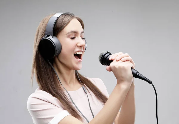 Ekspresyjna dziewczyna śpiewa z mikrofonu i słuchawek — Zdjęcie stockowe