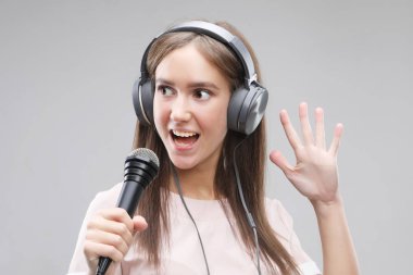  Bir mikrofon ve kulaklık ile şarkı söyleyen ifade kız