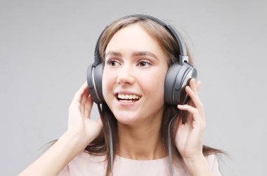 Kulaklıklı genç bir kadın müzik dinliyor.
