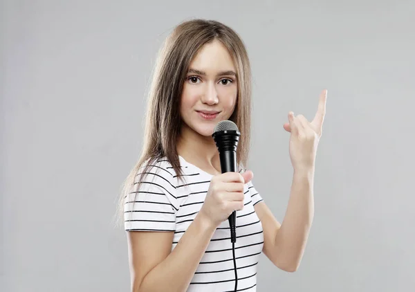 Belleza modelo chica cantante con un micrófono sobre fondo gris claro —  Fotos de Stock