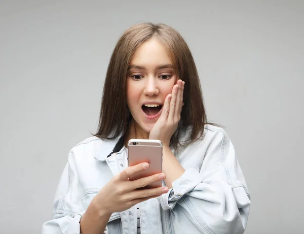 happy excited female glad to recieve text message, stares at mobile phone