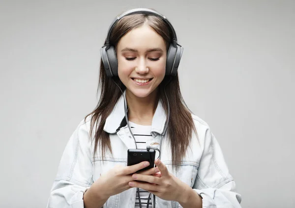 Hermosa mujer joven escuchando música en auriculares con teléfono inteligente —  Fotos de Stock