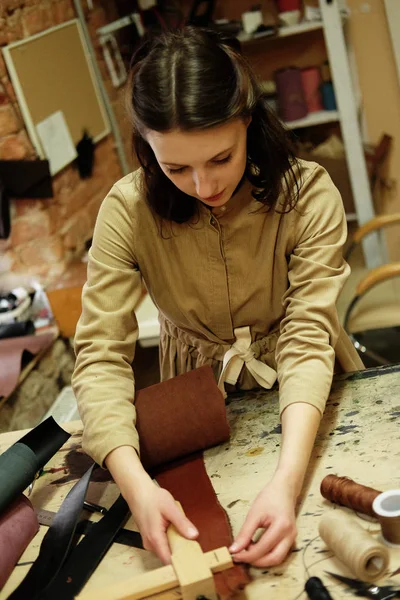 Femme travaille dans un studio de fabrication de sacs, découpe les détails — Photo