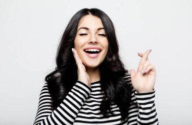 Neşeli genç kadın, parmaklarını çapraz kaldırır, arzu dilek yapar.