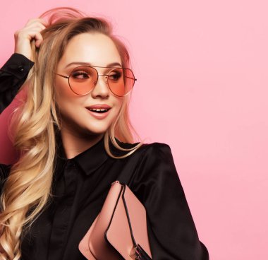 Bluz ve pantolon giyen, gözlük takan, el çantası tutan güzel sarışın kadın.